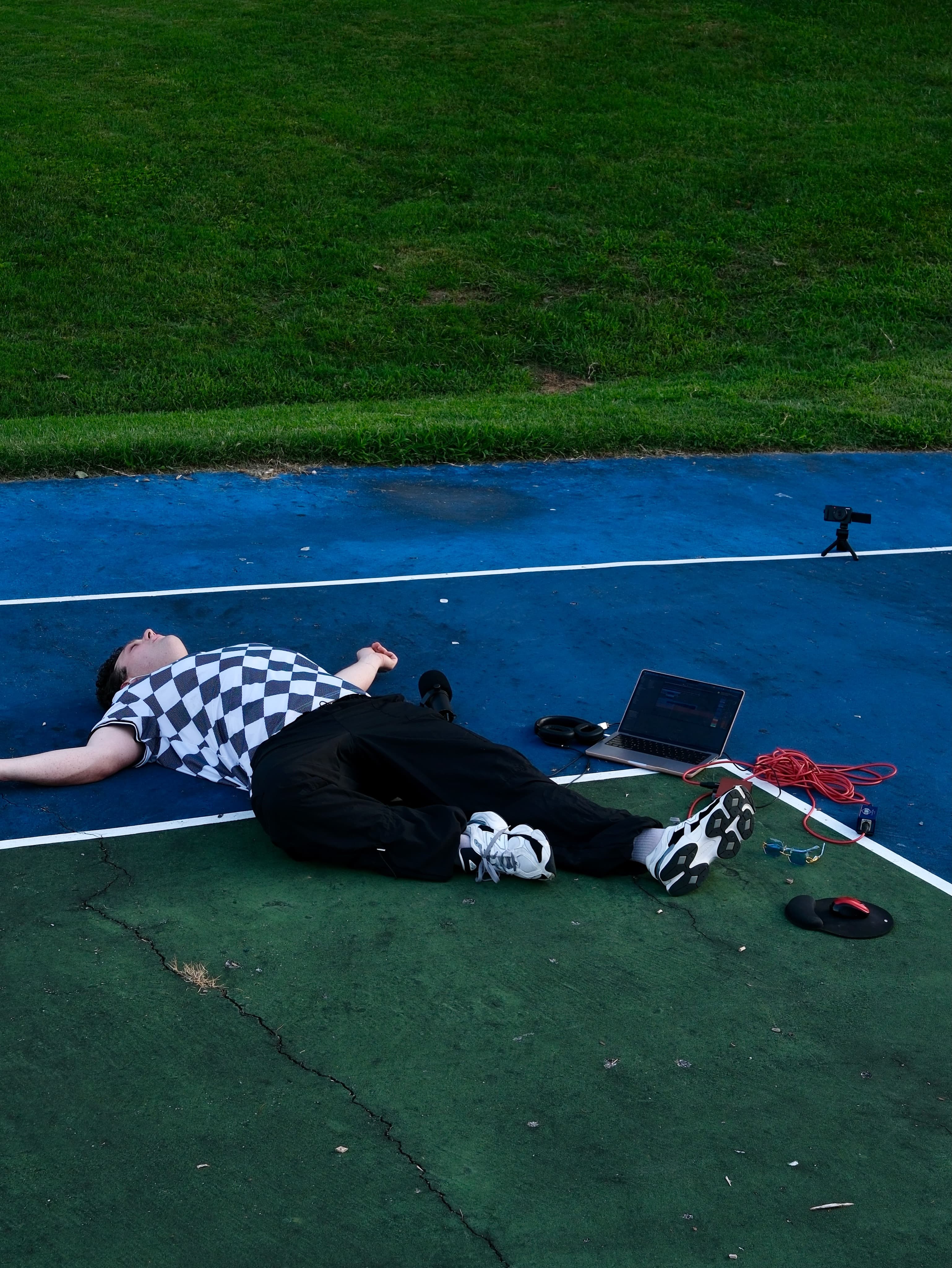 BRAVEN lying back with his arms out on the court beside his laptop and coiled red cables.